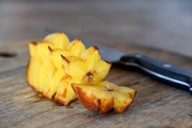 Çürük yıldız meyvesi, olgun meyvenin üzerinde, sarı renkli, kahverengi ahşap masaya yerleştirilmiş.