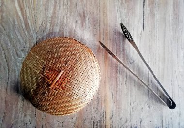 Kahverengi ahşap arka plana yerleştirilmiş metal maşayla bambu kaplama.