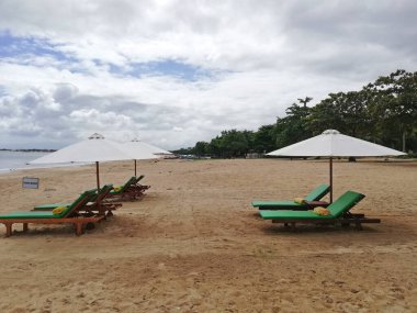 Bali Endonezya 'daki güzel Jimbaran plajı, güzel havalarda beyaz kum ve güneş yatağı