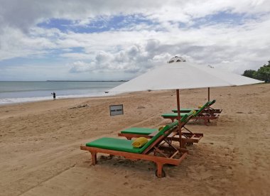 Bali, Endonezya - Temmuz 07.2022: Bali Endonezya 'daki güzel Jimbaran plajı, güzel hava koşulları altında beyaz kum ve güneş yatağı. Jimbaran plajı adanın ünlü bir turizm beldesidir.