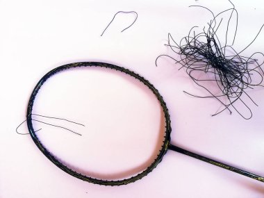 Bali,Indonesia - July 23,2022: Badminton racket with a broken strings,on color background