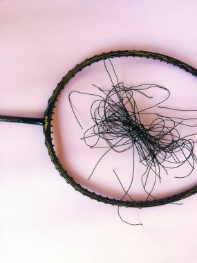 Bali,Indonesia - July 23,2022: Badminton racket with a broken strings,on color background