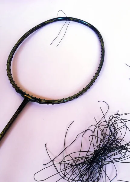 Bali,Indonesia - July 23,2022: Badminton racket with a broken strings,on color background