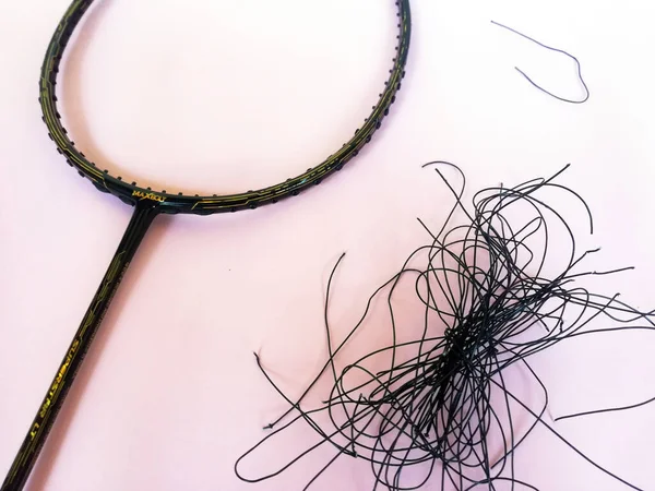 Bali,Indonesia - July 23,2022: Badminton racket with a broken strings,on color background