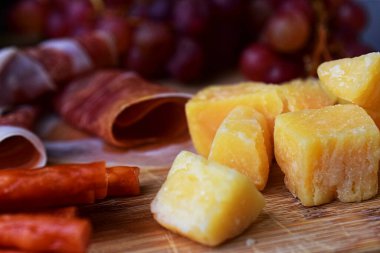 Sert peynir küplerine yakın çekim, sığ alan derinliği. Ahşap tahtada parmesan. Şarap çerezi..