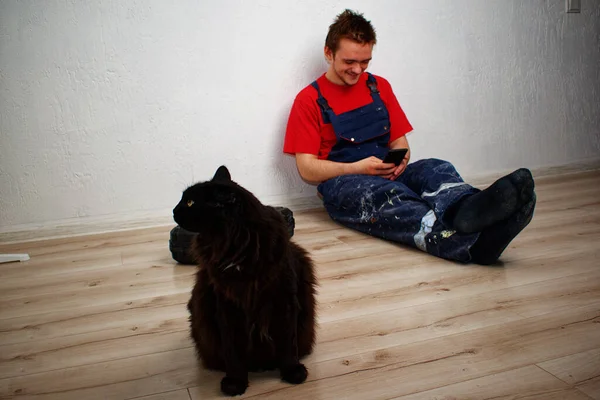 Black Cat Sits Laminate Background Construction Worker Robe Looking His — Stock Photo, Image