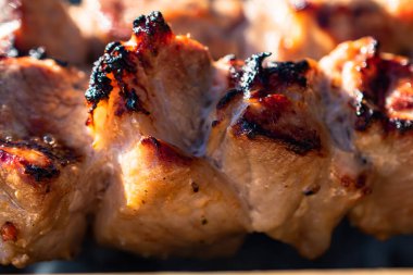 Bir şişte yakın plan kızarmış et parçaları. Lezzetli, sulu, tavuk ve domuz kebabı şişte kızartılır. Güneşli bir günde, açık havada barbekü. Barbeküden duman yükseliyor..