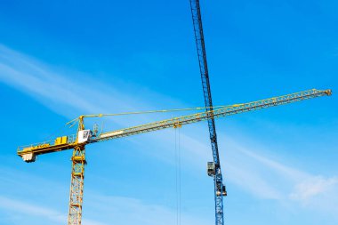 Riga, Letonya 'nın merkezinde açık mavi gökyüzüne karşı mavi ve sarı renkli vinçler inşa ediyoruz..