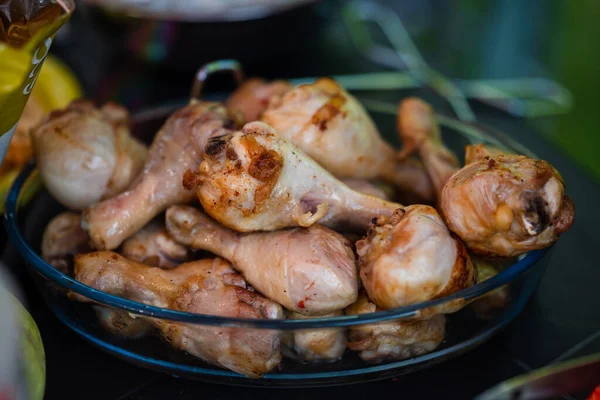 Fresh, juicy and fried chicken legs in a glass bowl on a black plastic table. Fresh and wholesome food. Small depth of field. Food in nature.