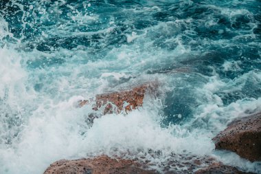 Close-up of water splashes against the breakwaters on the Balearic Sea. View from the pier on the beach of Barcelona, Spain.