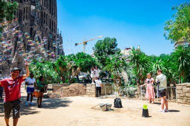 Barcelona, Spain - May 28 2022: In The Park In Front Of The Sagrada Familia, People Are Walking In The Park And Blowing Soap Bubbles.