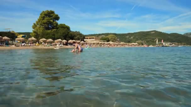 時間の息をのむ人々日光浴とビーチでの水泳 Moraitika ギリシャ 高品質4K映像 — ストック動画