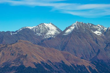 Parlak mavi gökyüzüne karşı vadilerde taş zirveleri ve ormanları olan güzel dağ manzaraları. Rusya 'nın Soçi şehrinde Gül Tepesi