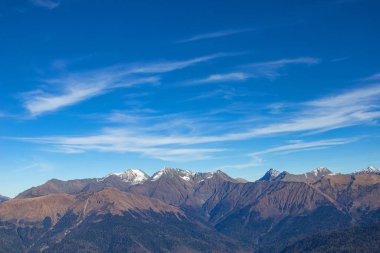 Parlak mavi gökyüzüne karşı vadilerde taş zirveleri ve ormanları olan güzel dağ manzaraları. Rusya 'nın Soçi şehrinde Gül Tepesi