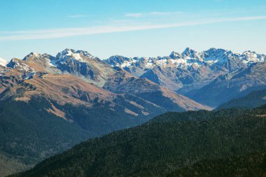Parlak mavi gökyüzüne karşı vadilerde taş zirveleri ve ormanları olan güzel dağ manzaraları. Rusya 'nın Soçi şehrinde Gül Tepesi