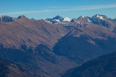 Parlak mavi gökyüzüne karşı vadilerde taş zirveleri ve ormanları olan güzel dağ manzaraları. Rusya 'nın Soçi şehrinde Gül Tepesi