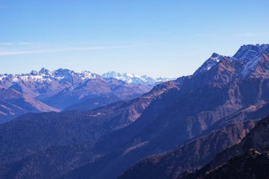 Görkemli dağ sırasının manzarası, mavi gökyüzüne karşı keskin tepeler yükseliyor. Gül Tepesi, Soçi, Rusya