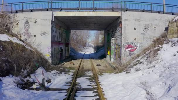 Hladký oblouk pod mostem s nápisy podél železnice