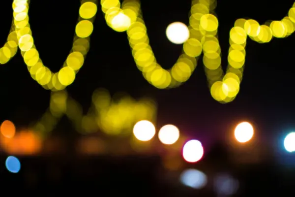 Festivalde siyah arkaplan ile kıvrımlı şekillerde sarı renkli Bokeh ışığı.