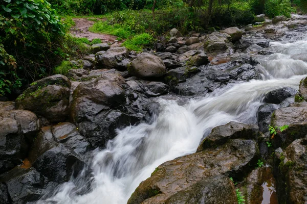 Rain water flowing at the base of waterfall during monsoon season.