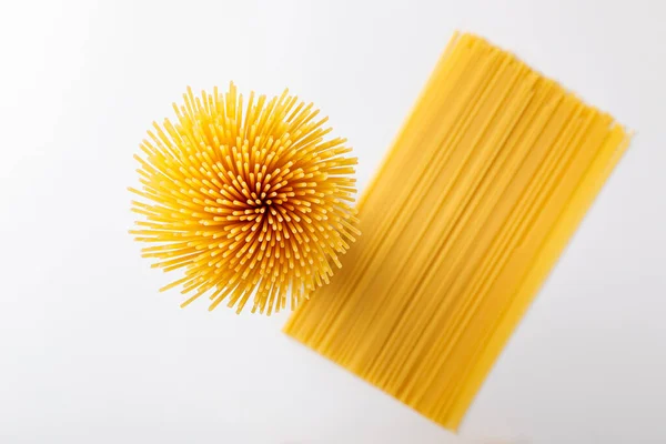 Dikey bir demet ve iple bağlanmış bir demet çiğ spagetti. Beyaz arka planda bir deste. Yukarıdan bak. İtalyan gıda konsepti.
