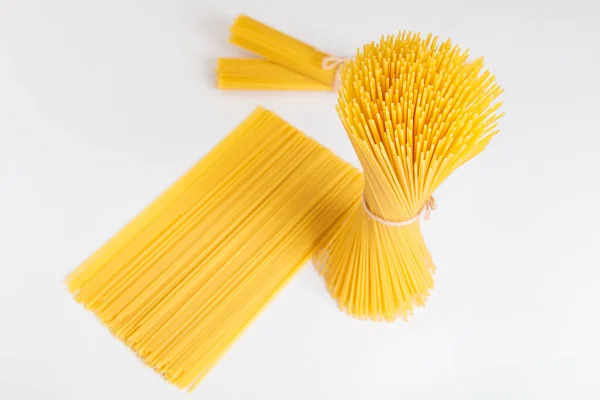 Beyaz arka planda iplikle bağlanmış çiğ spagetti paketleri. İtalyan gıda konsepti.