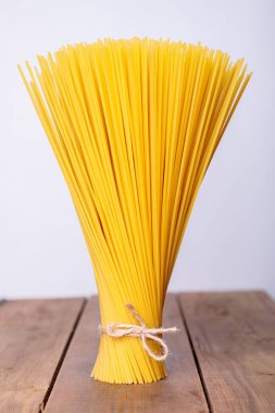 Dikey bir demet ve iple bağlanmış bir demet çiğ spagetti. Ahşap bir arka planda deste.