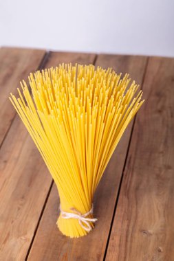 Dikey bir demet ve iple bağlanmış bir demet çiğ spagetti. Ahşap bir arka planda deste.