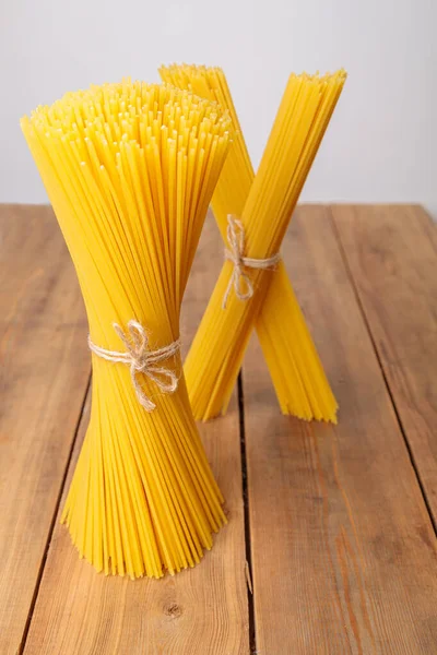 Вертикальна група і купа сирих спагеті пов'язаних з струною. Бульбашка на дерев'яному фоні . — стокове фото