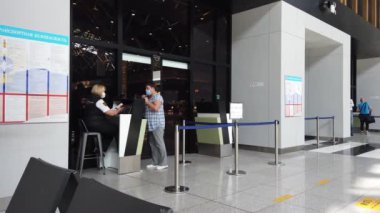 Maskeli yetişkin bir kadın havaalanındaki kasada pasaport kontrolünden geçiyor. Sheremetyevo. Moskova, Rusya 10 Kasım 2021