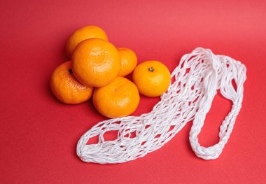 Kırmızı şenlik arka planında mandalinalı çevre dostu ağ. İsa 'nın Doğuşu bayramı.