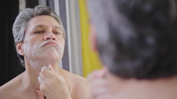 Adult Gray Haired Man Shaves Razor Front Mirror — Αρχείο Βίντεο