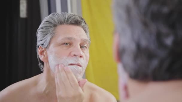 Dospělý Šedovlasý Muž Nanáší Krém Holení Obličej Před Zrcadlem Detailní — Stock video