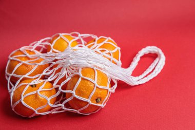 Kırmızı şenlik arka planında mandalinalı çevre dostu ağ. İsa 'nın Doğuşu bayramı.