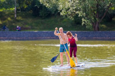 Bir çocuk sörf tahtasının üzerinde yüzüyor, kürekle itiyor. Sörf tahtası. Rusya Zelenograd 14 Ağustos 2021