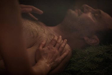 Bir kadın süpürgelerin yardımıyla bir erkek için banyo ritüeli gerçekleştiriyor. Bir adam ladin dallarına uzanır..