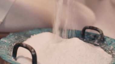 Spa tedavisi için yuvarlak bir kaseye beyaz tuz dökülüyor. Yakın plan..