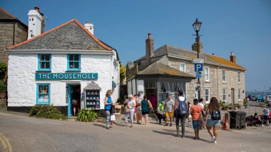 Mousehole, Cornwall, İngiltere. 2021 yılı. Tatilciler Cornish 'in kıyı kasabası Fare Deliği' nden alışveriş yapıyorlar. Güney Cornwall sahilinde manzaralı bir tatil beldesi..