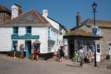 Mousehole, Cornwall, İngiltere. 2021 yılı. Tatilciler Cornish 'in kıyı kasabası Fare Deliği' nden alışveriş yapıyorlar. Güney Cornwall sahilinde manzaralı bir tatil beldesi..