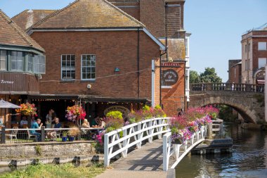 Newbury, Berkshire, İngiltere, İngiltere. 2021 yılı. Manzara, Newbury, İngiltere 'deki Kennet ve Avon kanallarının yanındaki eski kasaba köprüsüne ve çiçeklerle süslenmiş bir bara bakıyor..