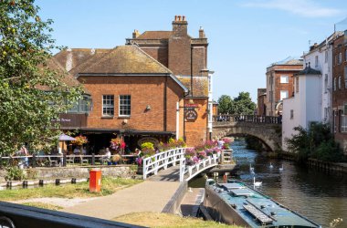 Newbury, Berkshire, İngiltere, İngiltere. 2021 yılı. Manzara, Newbury, İngiltere 'deki Kennet ve Avon kanallarının yanındaki eski kasaba köprüsüne ve çiçeklerle süslenmiş bir bara bakıyor..