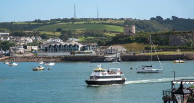 Plymouth, Devon, İngiltere, İngiltere. 2021 yılı. Barbican iniş sahnesine gelen tur teknesi Batten Dağı ve Batten Kulesi 'nin arka planına sahip.