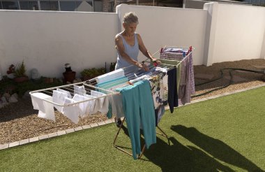 Güney Afrika. 2022 yılı. Yaşlı bir kadın güneşli bir günde bahçede kurumak için asılıyor..