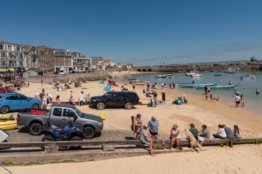 St Ives, Cornwall, İngiltere, İngiltere. 2022 yılı. Aziz Ives, popüler bir Cornish sahil beldesi. Kumsaldaki tatilciler ve kumsaldaki araçlar..