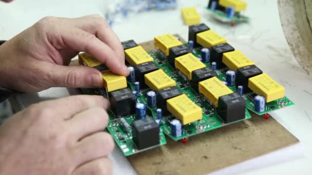 A man collects radio components. He puts it on the board and soldering it with a soldering iron. Assembly of the electrical part of the device by human hands. Electrical parts. Solder with tin. — Stock Video
