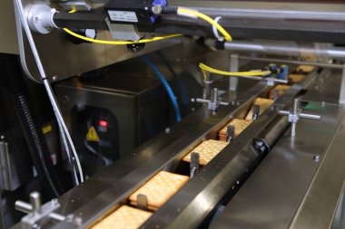 Üretim hattında bir sürü kurabiye var. Paketlemeden önce tatlı akışı. Makinede kraker paketliyorum. Yenilikçi üretim