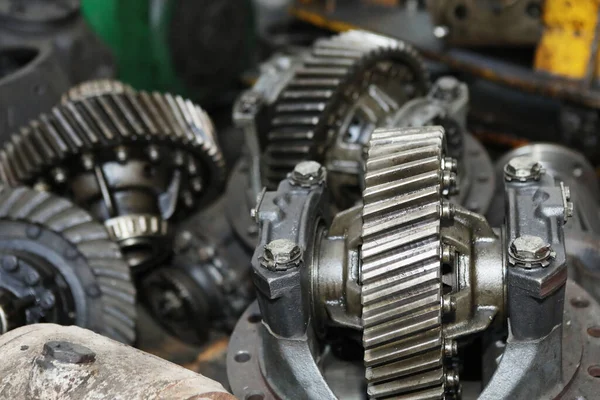 Large gears of a truck. The engine and shaft with gears are disassembled. Black, metal engine parts