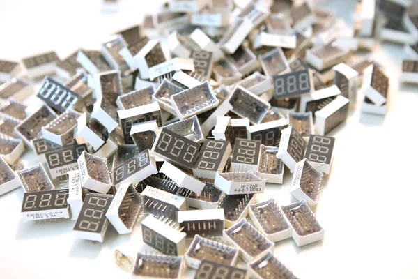 Lots of radios. Loose electronic parts on the table. Digital indicator, LEDs, capacitor and microcircuits in a pile.