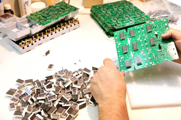 A man collects a printed circuit board. The worker solders the radio components and assembles the finished device. Manual assembly and control