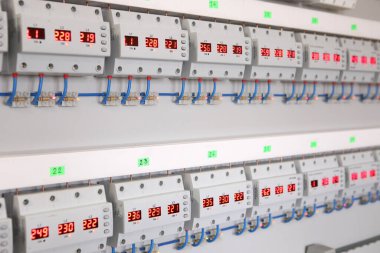 Service center for the repair of power voltage relays. Human checking electrical device with digital display. Numbers on the test bench. Manufacture of sockets volt control and quality control..